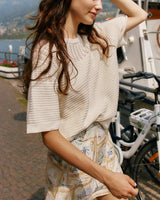 Cream-colored cotton knitted tee with a round neckline and textured yoke detail, worn with patterned shorts.