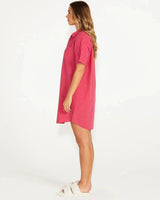 Woman wearing a pink and magenta pinstripe cotton button-through night shirt with short sleeves.