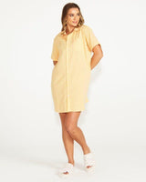 Woman wearing a yellow pinstripe cotton button-through night shirt with short sleeves.