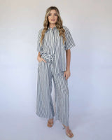 Woman wearing a relaxed, black and white vertical striped cotton-viscose shirt and matching wide-leg trousers.