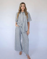 Woman wearing a relaxed, black and white striped cotton-viscose button-down shirt and matching wide-leg pants.
