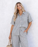 Woman wearing a relaxed, short-sleeve Clementine shirt in a breathable black and white vertical stripe cotton blend.