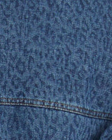 Close-up of the Cleo cropped denim jacket featuring a textured blue leopard print pattern and stitched seam detail.