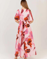 Back view of a pink floral cotton maxi dress with gathered sleeves and a wrap-tie waist detail.