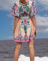 Back view of a Cali Pink linen-blend mini dress with puff sleeves, a belted waist, and a vibrant floral print.