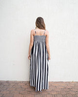 Woman wearing a black and white striped cotton maxi dress with a straight neckline and adjustable spaghetti straps.