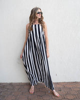 Woman wearing a black and white striped cotton maxi dress with a straight neckline and adjustable spaghetti straps.