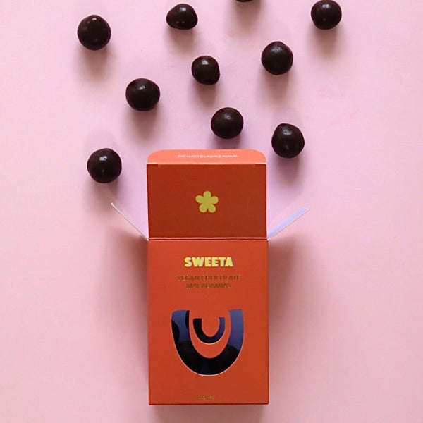 Orange packaging with black berries on a pink background