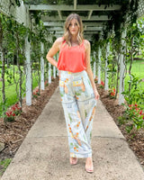 Coral scoop-neck Dashing Tank in drapey viscose-silk blend, worn with patterned wide-leg trousers in a garden setting.