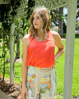 Woman wearing a bright coral scoop-neck Dashing Tank in drapey viscose-silk blend with thick straps.