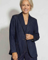 Woman wearing a dark denim Destiny blazer with a relaxed fit, shawl collar, and front patch pockets.