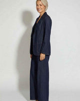 Woman wearing a dark denim Destiny blazer with a relaxed fit and notched lapels over matching wide-leg jeans.