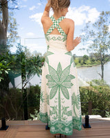 Woman wearing a green and cream palm print linen-cotton maxi dress with a crisscross back and A-line silhouette.