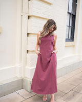 Wine-colored cotton-linen tank maxi dress with a round neckline and side pockets, worn outdoors.