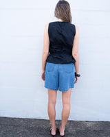Black cotton sleeveless top with a back keyhole detail and gathered waist, worn with blue denim shorts.