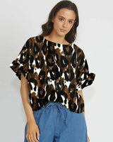 Model wearing a brown and black leopard print Ella reversible top with short ruffled sleeves and a high neckline.