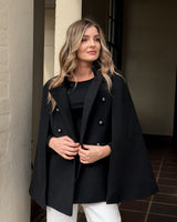 Black wool-blend military cape with a high neckline, double-breasted silver buttons, and a structured boxy silhouette.