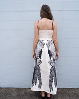 Back view of a cream linen-blend sundress with black tropical print, adjustable straps, and a shirred back.