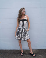 Woman wearing a black and white floral linen-blend Eloise mini dress with a square neckline and side pockets.