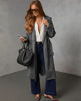 Woman wearing a charcoal grey suede trench coat with double-breasted buttons, styled over a white shirt and dark jeans.