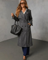 Woman wearing a charcoal grey suede double-breasted trench coat with a belted waist, size small.