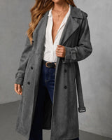 Grey suede trench coat with a double-breasted button front, belted cuffs, and a notched lapel collar.