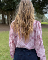 Woman wearing an orchid pink plaid pussybow blouse with long sleeves and a relaxed fit, viewed from behind.