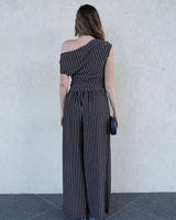 Woman wearing a one-shoulder metallic stripe jersey top with ruched detailing and matching wide-leg trousers.