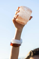 Hand-carved Saltist Himalayan salt margarita glass held up against a clear blue sky.
