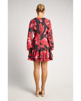 Back view of a black mini dress with a bold red floral print, long sleeves, tie waist, and a layered ruffle hem.