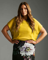Model wearing a vibrant mustard yellow short-sleeved knit top with a soft, structured fit.