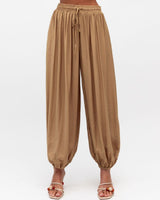Caramel balloon-silhouette pants with an elastic drawstring waist and gathered cuffs in a soft rayon-nylon blend.
