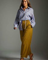 Model wearing relaxed-fit chartreuse Good Karma pants with an elastic drawstring waistband and a blue striped shirt.