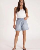 Model wearing high-waisted Capri Blue rigid denim mom shorts with a relaxed fit and zip fly.