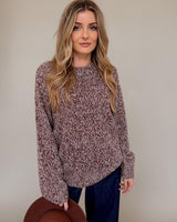 Woman wearing a relaxed-fit, multi-colored knit sweater with a classic neckline and ribbed detailing.