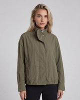 Woman wearing a green jacket against a gray background