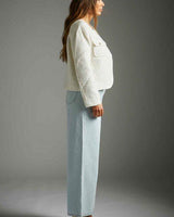 Woman wearing a cream-colored boucle Harmony jacket with structured shoulders and front pockets, paired with light-wash jeans.