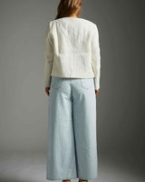 Back view of a cream-colored boucle Harmony Jacket with a structured fit, paired with light wash wide-leg jeans.