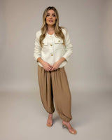 Cream-colored boucle Harmony jacket with gold buttons, styled with relaxed tan trousers and clear heeled sandals.