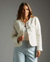 Cream-colored boucle jacket with a structured collarless design, gold button closures, and two front flap pockets.