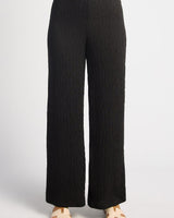 Black high-waisted straight-leg pants in textured jersey fabric with a clean, minimalist silhouette.