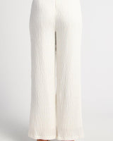 Back view of high-waisted white textured jersey pants with a straight-leg cut and invisible back zip.