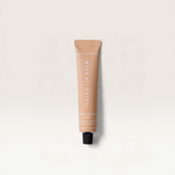 House of Holabox Addition Studio Dawn tinted lip balm in a 15ml squeeze tube with a warm, subtle peach-toned hue.