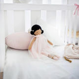 House of Holabox Alimrose Lulu doll with dark hair in buns wearing a pink tulle dress sitting on a soft bed
