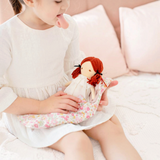 House of Holabox Alimrose Mini Matilda soft doll with red yarn hair being held by a child in a white dress