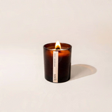 House of Holabox saide. large amber soy candle with a lit wood wick in a glass jar, clove and sandalwood scent.