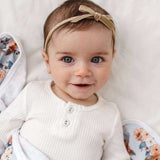 House of Holabox Snuggle Hunny baby wearing a soft beige velvet bow headband on a white ribbed long sleeve top