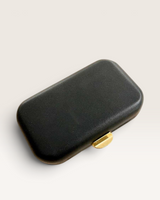 House of Holabox Rhea Classic black faux leather box clutch with a gold metal clasp closure.