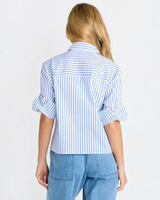 Back view of a woman wearing a House of Holabox blue and white striped cropped poplin shirt with cuffed sleeves.