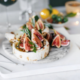 House of Holabox Coast to Coast ceramic brie baker topped with fresh figs and herbs on a marble serving board